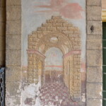 Iluzivní architektura u vchodu z parku. Stav před restaurováním: zvlášť spodní partie jsou výrazně poškozené