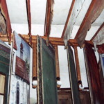 Pohled mezi boční kulisy před vyklizením divadla a restaurováním. Kulisy se pohybují v primitivních drážkách, mezi nimi jsou umístěny lampy, narubu prken ještě s původním elektrickým vedením